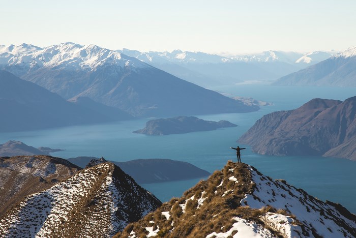 Person on snowy mountain peak overlooking Wanaka lake