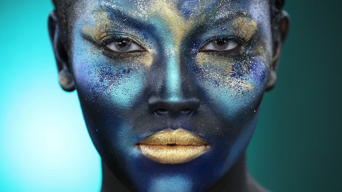 Woman with blue and gold glitter face paint