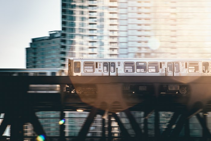 Chicago train moving past buildings with sun flare
