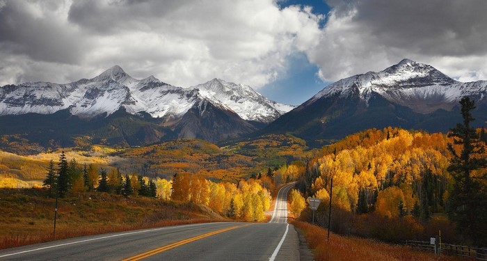 Road leading to snow-capped mountains in fall