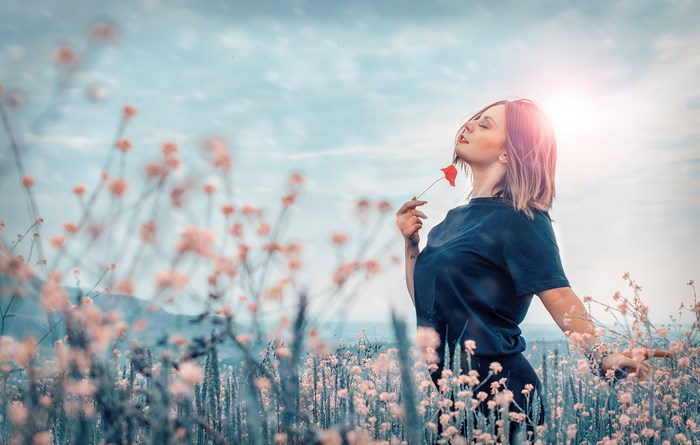 Woman in a field holding a red flower