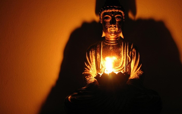 Buddha statue with candle light and shadow