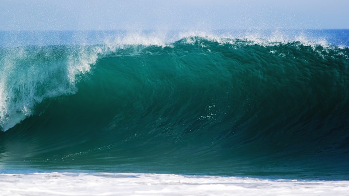A large turquoise wave breaks in the ocean