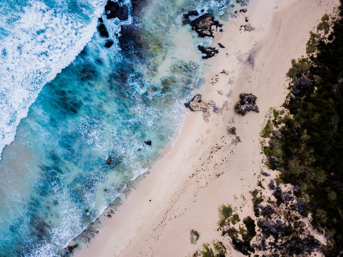 Aerial view of a rocky beach with turquoise ocean waves