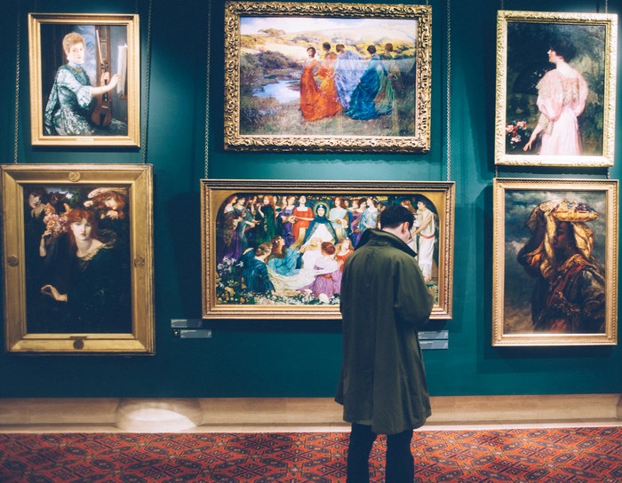Man Browsing Paintings in an Art Gallery