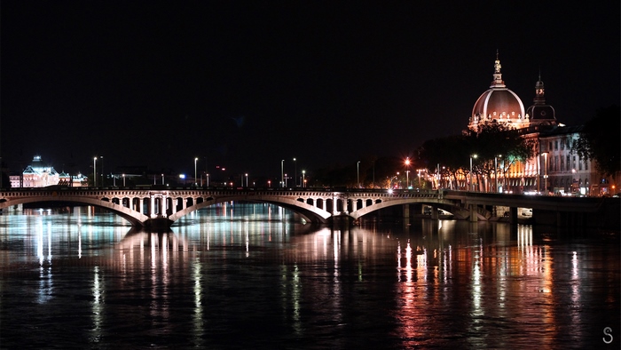Night view of a bridge and illuminated buildings in Lyon, France