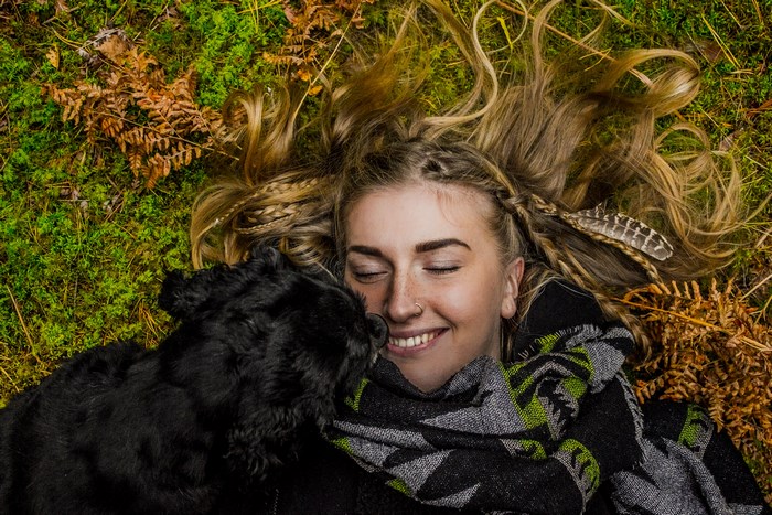 Woman and dog lying in autumn nature