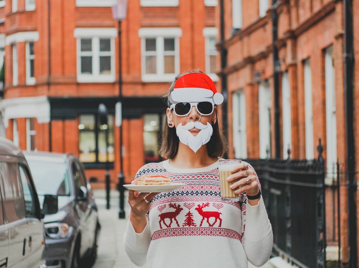 Woman in Santa costume holding a drink and cake