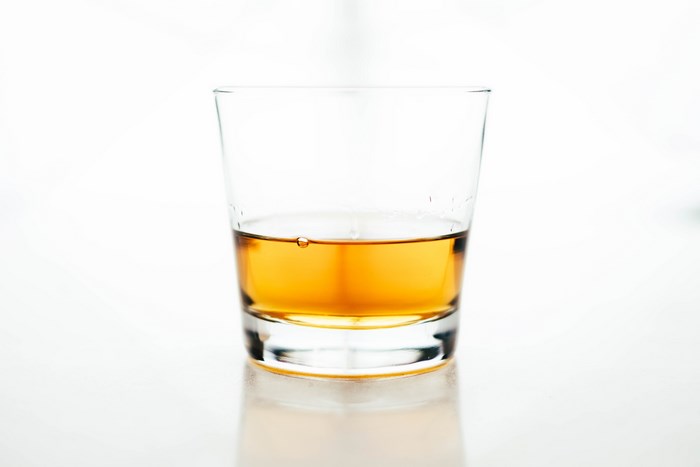 Glass of amber whiskey on a white surface
