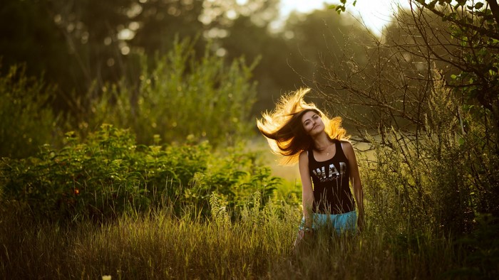 Woman with windblown hair in a sunlit field