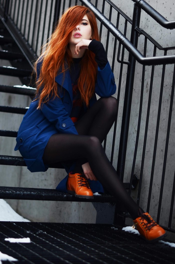 Woman with long red hair sitting on stairs