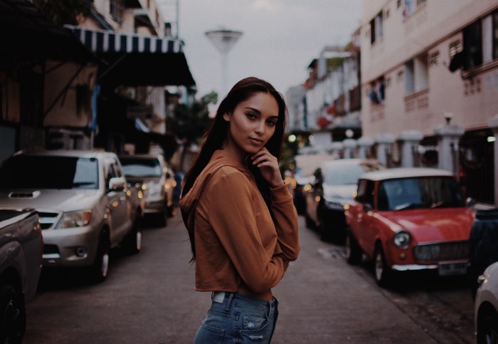 Woman in orange hoodie and jeans on a street