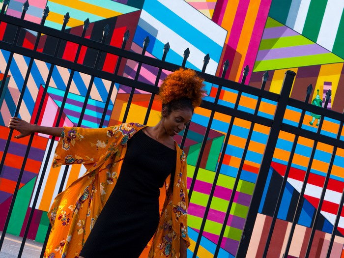 Woman in orange kimono in front of colorful mural