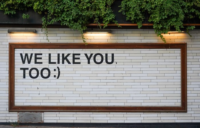 We Like You Too sign on a tiled wall