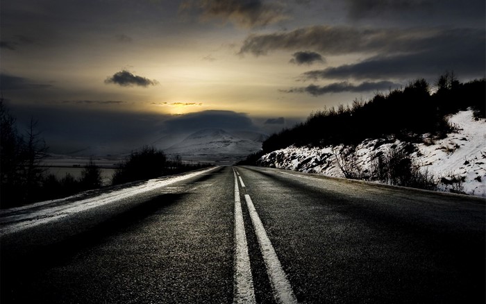 Road through snowy landscape at sunset