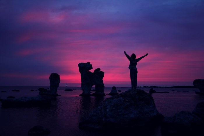 Woman silhouetted against a vibrant sunset over the sea