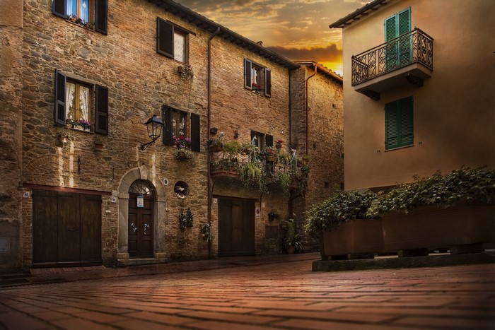 Tuscan street with brick buildings and balconies at sunset