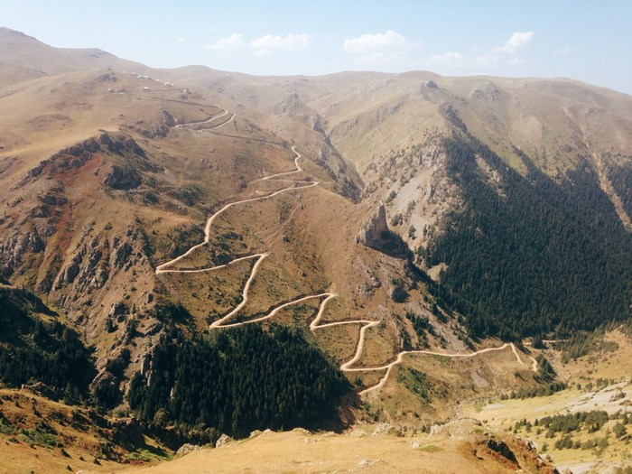 Winding mountain road through a valley with forests