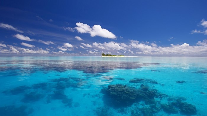 Tropical island in a clear blue ocean under a cloudy sky