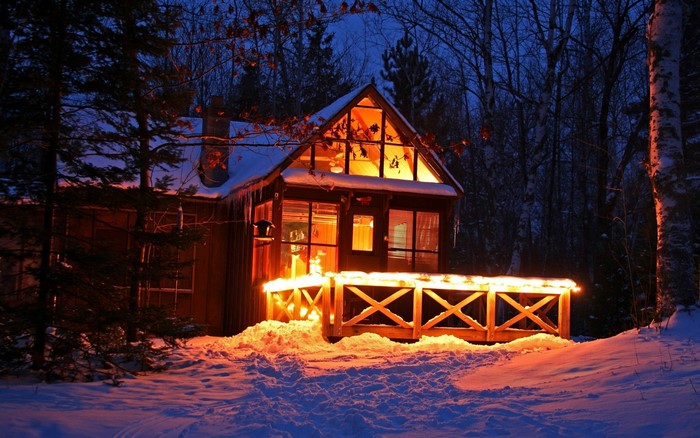 Cozy Winter Cabin Illuminated at Night in Snowy Forest