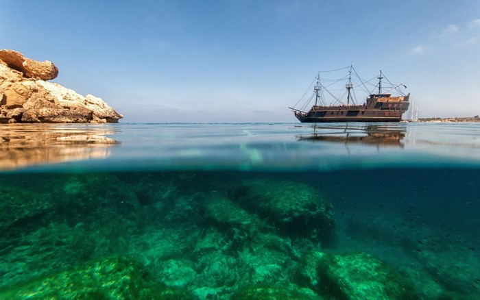Split view of a pirate ship and underwater rocks