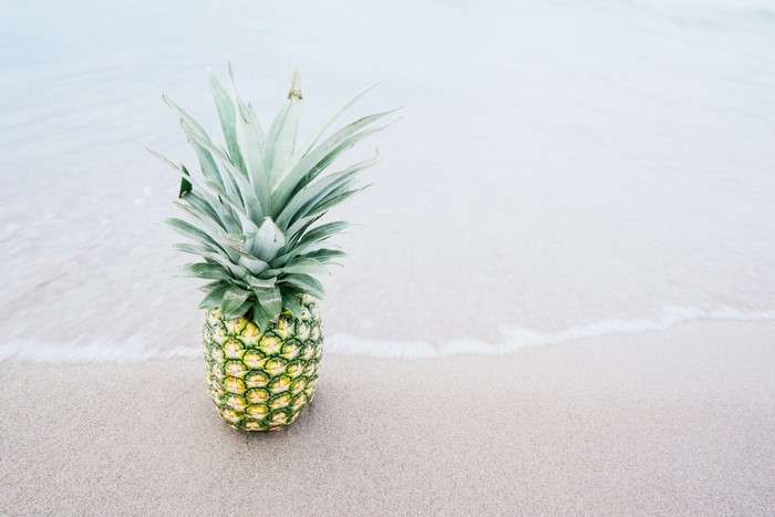 Pineapple on a sandy beach with waves