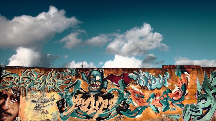 Graffiti on a wall with clouds and sky