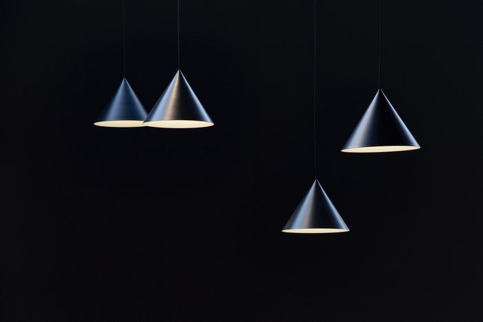 Four black cone-shaped pendant lights against a dark background