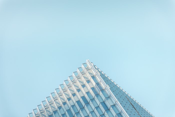 Modern glass building corner against a clear blue sky