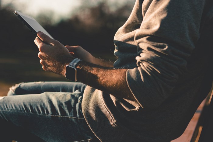 Man with Apple Watch and iPad Pro outdoors at sunset