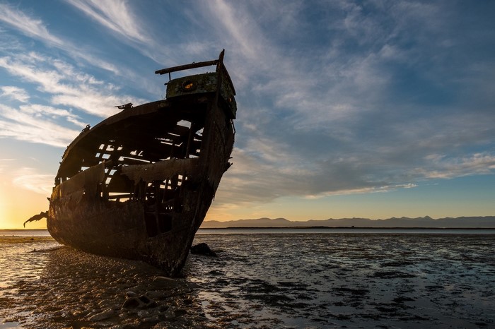 Abandoned shipwreck on a beach at sunset