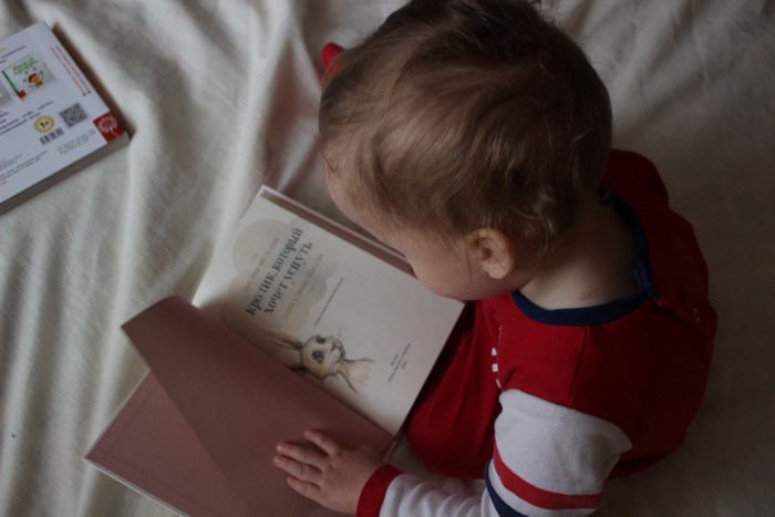 Baby reading a book on a bed