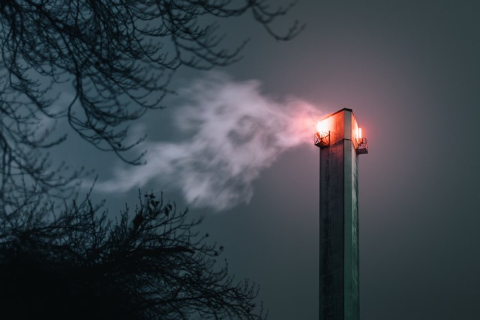 Chimney emitting smoke at night with trees
