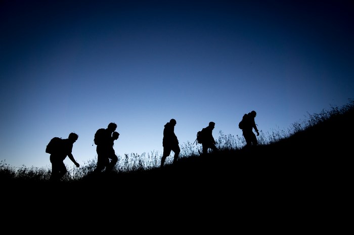 People hiking up a hill at dusk