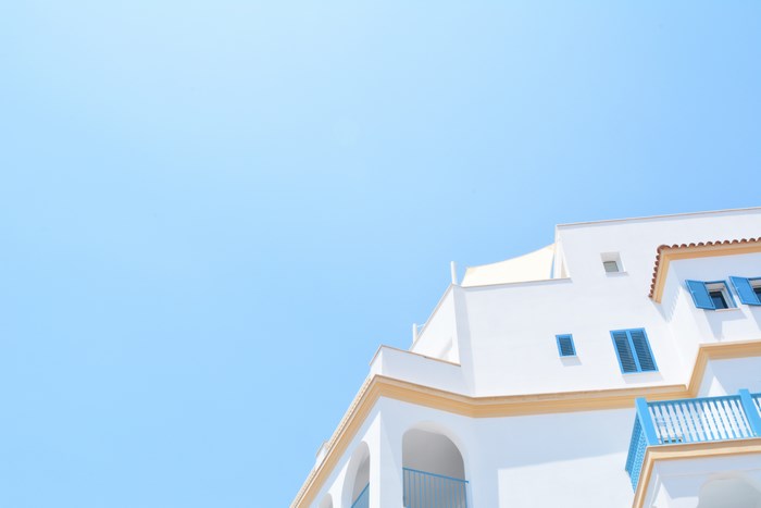 White building with blue shutters against a clear blue sky
