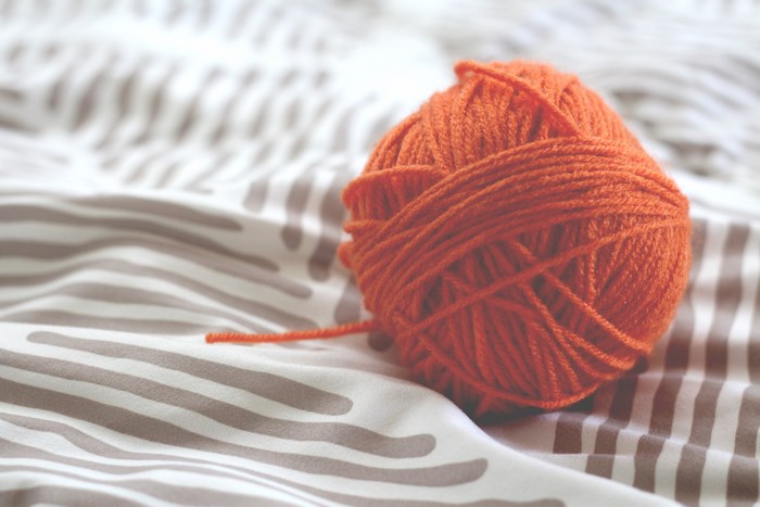 Orange ball of yarn on a striped blanket