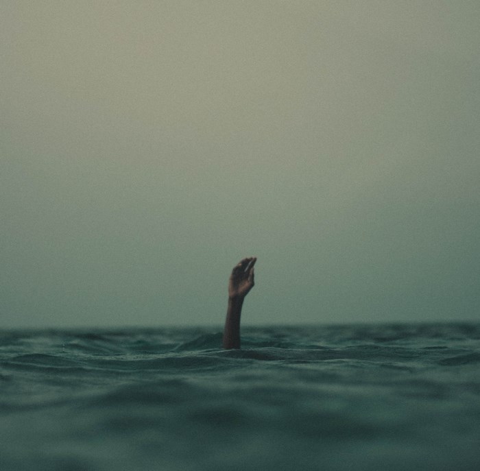 Hand reaching out of dark ocean water