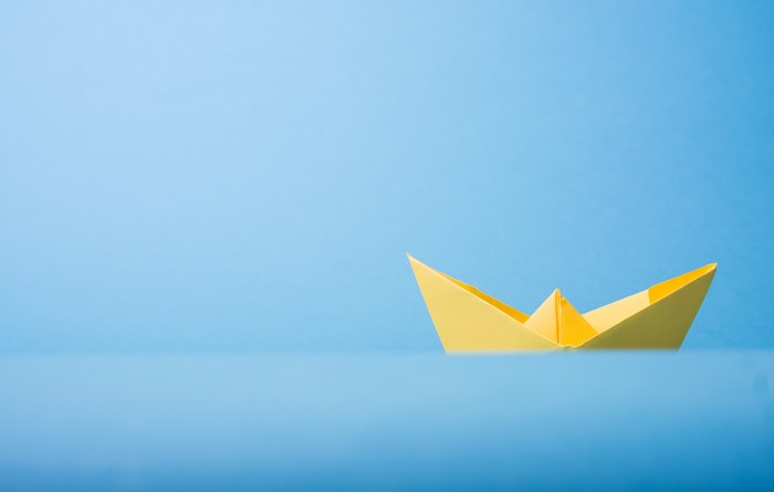 Yellow origami boat floating on blue water