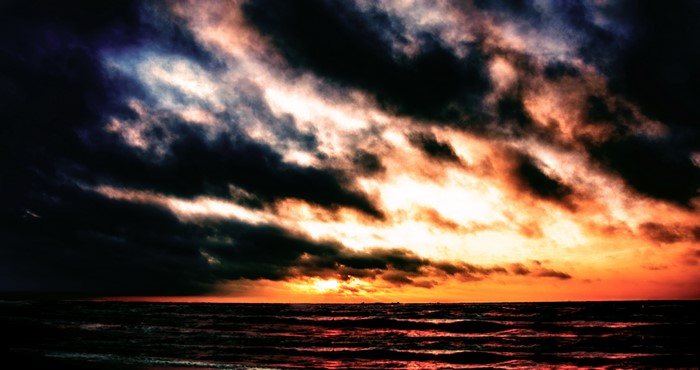 Dramatic sunset over the ocean with dark clouds