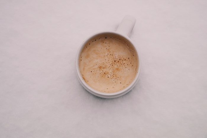 A cup of coffee with foam on snow