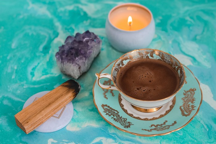 Teacup with coffee, amethyst, palo santo, and candle