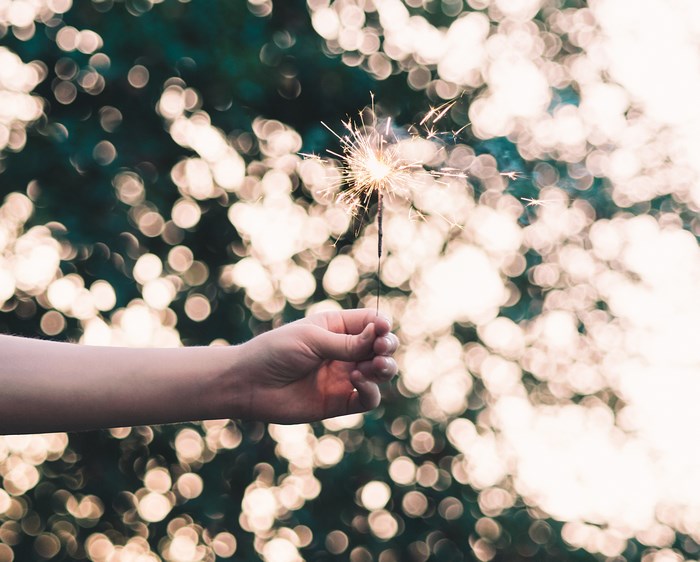 Hand holding a sparkler with bokeh background