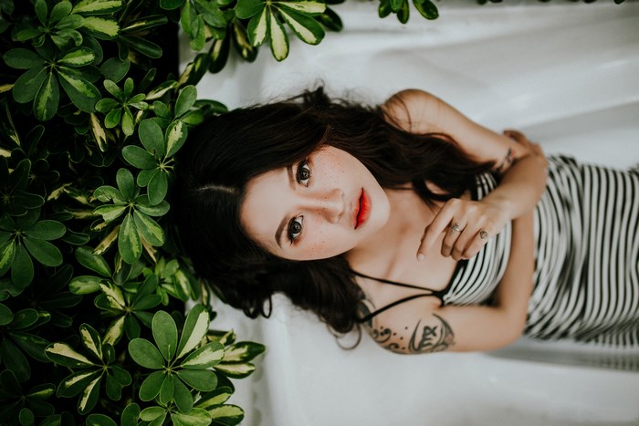 Woman with tattoos lying near green plants