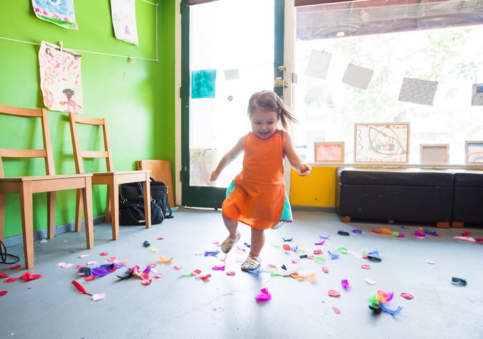 A young girl plays with colorful feathers on the floor