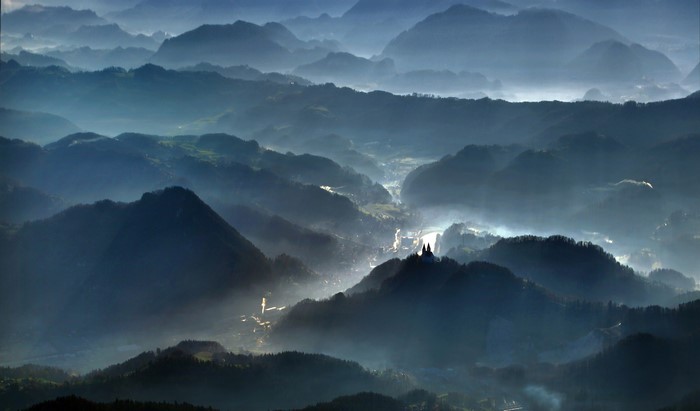 Misty blue mountains with a village in the valley