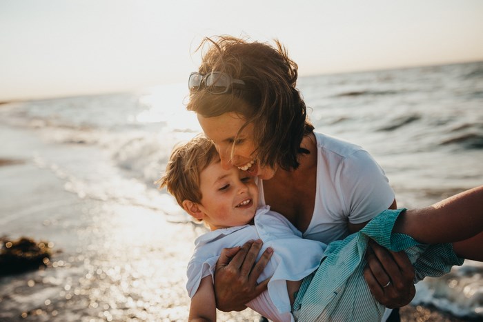 Mother holding her son on a beach at sunset