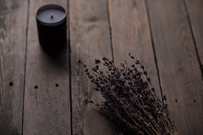 Dark candle and dried lavender bouquet on a wooden table