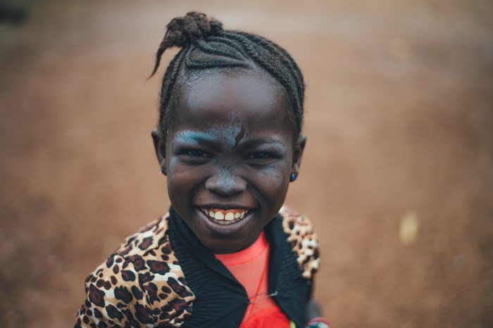 African girl with braids and face paint smiles