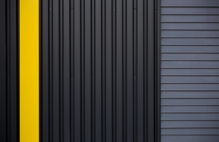Modern building facade with yellow stripe and corrugated metal