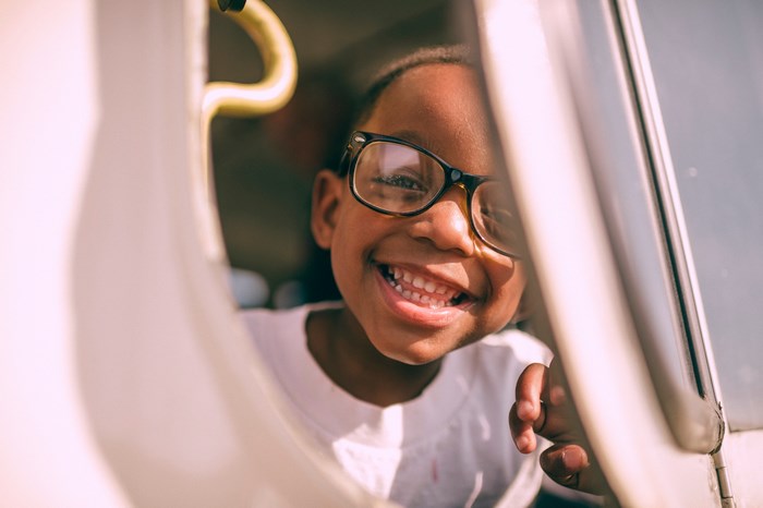 Happy child with glasses looking out of a car window